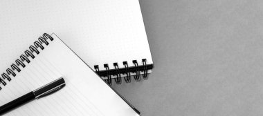 Boş bir sayfada spiral ve kalem olan bir defter. Tarafsız gri dokulu arka plan. Yukarıdan görüntüle