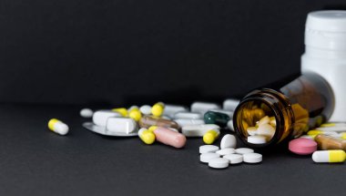 İlaç şişesi siyah üzerine çeşitli ilaçlar döküldü..