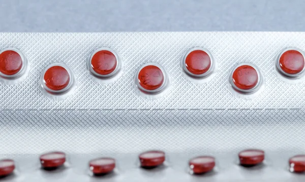 Red tablets in blister pack, silver aluminium foil pack for capsule and tablets pills in pharmaceutical industry.