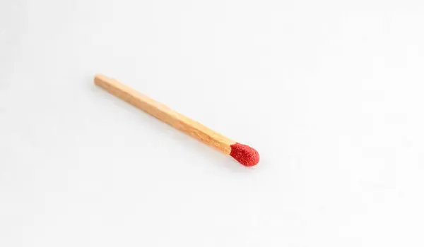 Close up of match on white. Single red match stick.