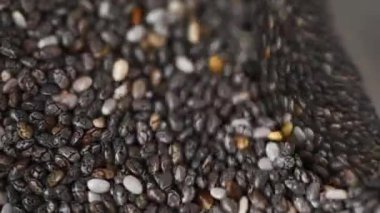 Chia tohumları parlak bir kaşıkla karıştırılır. Üst görünüm ve seçici odaklanma. Sağlıklı beslenme. Tarım ve tohum yetiştirme.