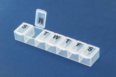 İlaç organizatörü, mavi arka planda ilaç kutusu yakın plan. O günün haplarını alma organizasyonu.