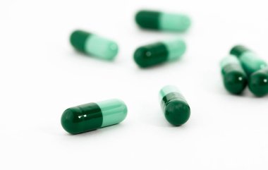 Beyaz arka plana yayılmış yeşil kapsüllere odaklan. Küresel sağlık hizmeti kavramı.