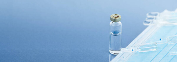 Mask and ampoules on a blue background with copy space, vaccination concept, coronavirus vaccination, ampoules.