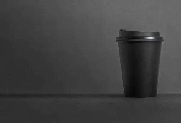 Black background take away paper coffee cup with copy space.
