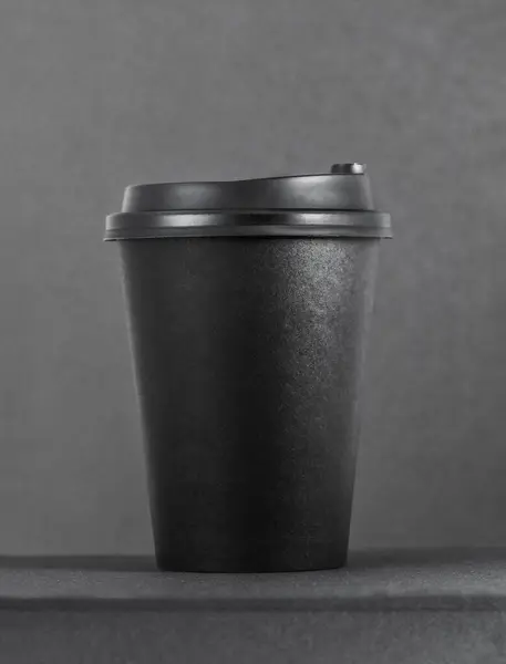 Takeaway coffee cup on black table and dark background.