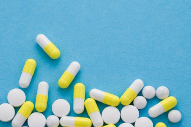 Mavi arka planda çeşitli ilaç hapları, haplar ve kapsüller. Uzayı kopyala, düz yat