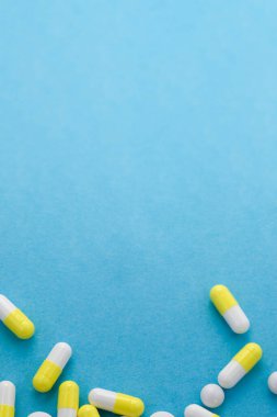 Mavi masada çeşitli beyaz ve sarı haplar var. Tıbbi, eczane ve sağlık hizmetleri konsepti. Uzayı kopyala Metin veya logo için boş yer.