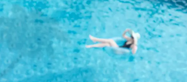 Girl on blue inflatable in swimming pool enjoying her vacation, laying in the pool ring