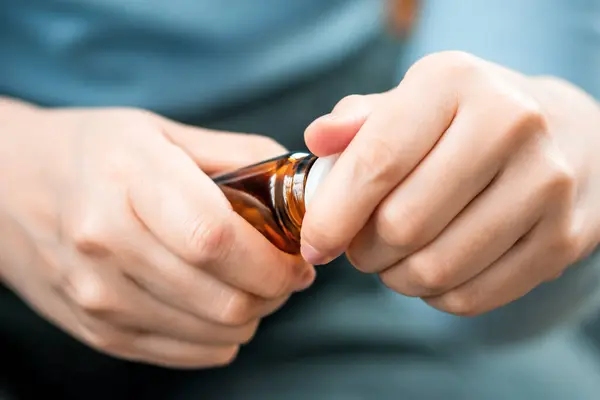 Bir kadının eli bir şişe ilaç, vitamin ya da besin takviyesi açar. Yaşlı insanların sağlığıyla ilgilenmek.