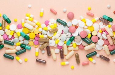 Pembe arka planda çok farklı haplar. Reçeteli haplar ve vitaminler. Metin için düz ve boşluk