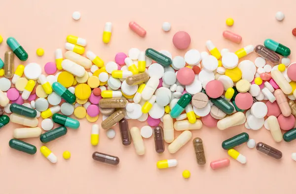 Pembe arka planda çok farklı haplar. Reçeteli haplar ve vitaminler. Metin için düz ve boşluk