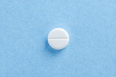 White tablet pill on blue background with copy space. Health concept clipart
