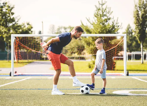 stock image A man with child playing football outside on field