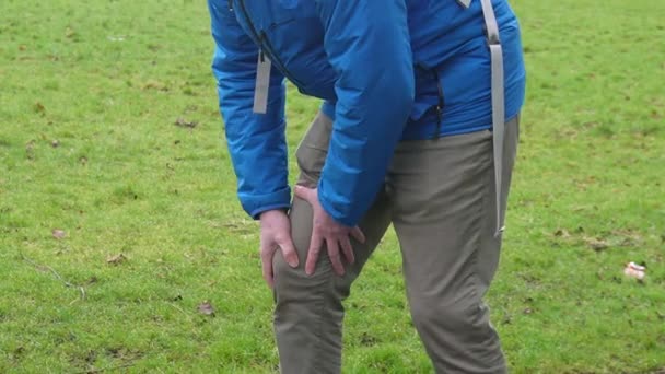 运动伤害的概念 男子在公园里跑步时双手紧紧抓住膝盖 — 图库视频影像