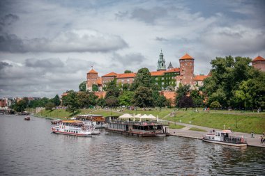 Zevkli tekneler ve turistlerle dolu Vistula Nehri 'nin hareketli nehri. Hepsi Polonya' nın Krakow kentindeki tarihi Wawel Şatosu 'nun gözetimi altında.