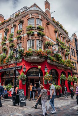 Londra 'daki hareketli bir sokak sahnesinde tarihi Crown and Anchor barı çiçek desenli cepheleriyle ve yaya geçitleriyle
