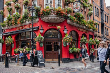 Londra 'daki hareketli bir sokak sahnesinde tarihi Crown and Anchor barı çiçek desenli cepheleriyle ve yaya geçitleriyle
