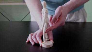 Eğitim amaçlı kalça esnekliği mekaniğini göstermek için ahşap anatomik model kullanan bir fizyoterapist.