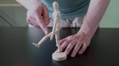 Eğitim amaçlı kalça genişletme mekaniğini göstermek için ahşap anatomik model kullanan bir fizyoterapist.