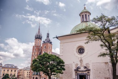 Polonya 'nın Krakow kentindeki St. Marys Bazilikası ve St. Adalberts Kilisesi parçalı bulutlu gökyüzüne karşı tarihi mimari sergileniyor.