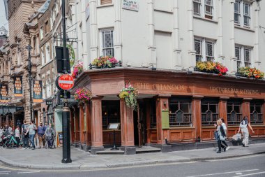 14 Temmuz 2024 'te Londra' nın geleneksel bir barı olan Chandos, hareketli bir sokak köşesinde çiçek sergileri ve şehrin cazibesini sergileyen insanlar.