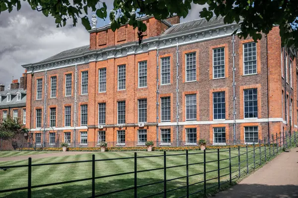 Kensington Sarayı 'nın dış cephesinde tarihi kırmızı tuğlalar ve Londra' da güneşli bir günde iyi manikürlü çimenler var.