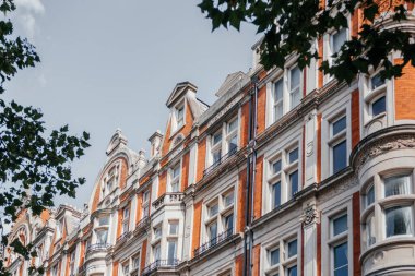 Londra 'daki tarihi kırmızı tuğla bina cephesine yakın plan, Victoria dönemi mimari detayları sergileniyor.