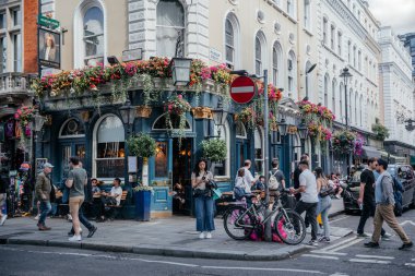 24 Temmuz 2024 'te canlı bir Londra meyhanesi. Canlı çiçeklerle süslenmiş, kalabalık bir caddede yürüyen ve dışarıda oturanların keyfini çıkaran bir bar.