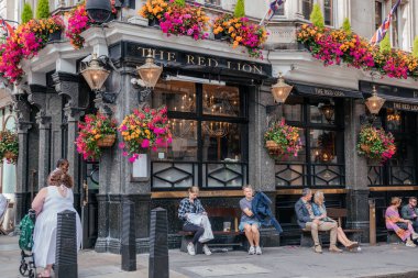 24 Temmuz 2023 Londra 'daki Red Lion Pub' da canlı çiçek süslemeleri, banklar ve klasik İngiliz atmosferi ile geleneksel bir cephe bulunmaktadır.