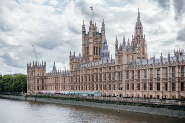 İngiliz Parlamentosu 'na ev sahipliği yapan Westminster Sarayı Thames Nehri boyunca görkemli bir şekilde duruyor ve ikonik Gotik mimarisini gözler önüne seriyor.