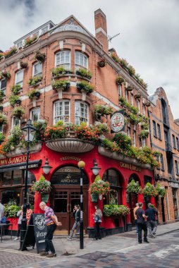 Londra 'daki hareketli bir sokak sahnesinde tarihi Crown and Anchor barı çiçek desenli cepheleriyle ve yaya geçitleriyle