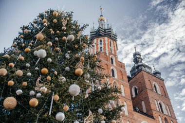 A beautifully decorated Christmas tree with gold and silver ornaments set against the historic St. Marys Basilica in Krakow, showcasing a festive holiday atmosphere clipart