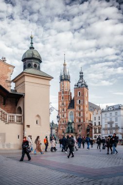 18 Aralık 2024 Krakow Eski Kasabası 'nda ikonik St. Mary Bazilikası, tarihi mimari ve hareketli atmosferden hoşlanan insanların yer aldığı canlı bir meydan.