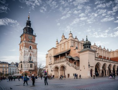 18 Aralık 2024 Krakow 'un ana meydanındaki tarihi Belediye Binası Kulesi ve Kulesi, canlı atmosfer ve mimari yapıların tadını çıkaran insanlarla çevrili.