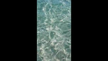 Dalgalanan güneş ışığı yansımaları ile berrak turkuaz suyun yakın görüntüsü, doğa, rahatlama ve tatil temaları için ideal.