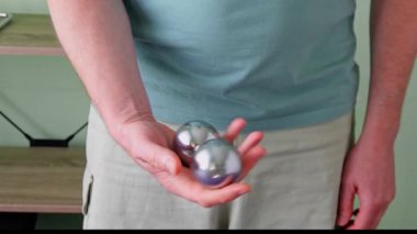 Stresten kurtulmak, rahatlamak, el esnekliği ve meditasyon yapmak için avucunda Çin Baoding topları yuvarlayan bir adam.