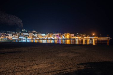 İtalya, Palermo 'daki Mondello Sahili' nin sakin bir gece manzarası sakin denizi yansıtan canlı şehir ışıklarıyla huzurlu bir sahil atmosferi yaratıyor.