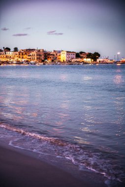 Mondello sahilinin gece görüşü, sakin denizi yansıtan deniz manzaralı binalar.