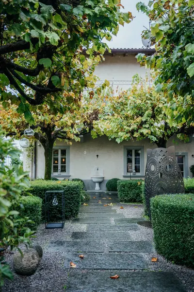 Bergamo, İtalya 'daki huzurlu bahçe bahçesinde manikürlü çitler, modern bir baykuş heykeli, taş patika ve dekoratif bir duvar çeşmesi bulunuyor.