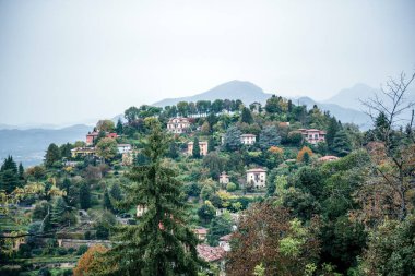 İtalya 'nın Bergamo kentindeki ağaçlar ve doğa ile çevrili dağ manzaralı villalar kırsal yaşam ve İtalyan manzaralarını resmetmek için ideal.
