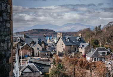 İskoçya, Oban 'da manzaralı dağ manzaralı ve kıyı atmosferli geleneksel taş evler, seyahat ve mimari temalar için ideal.