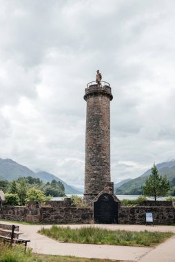 Glenfinnan Anıtı, İskoçya Dağları 'nda durmakta dramatik bulutlu gökyüzü ve çevresindeki yeşil tepelerle, miras, seyahat ve tarihi turizmi resmetmek için idealdir.