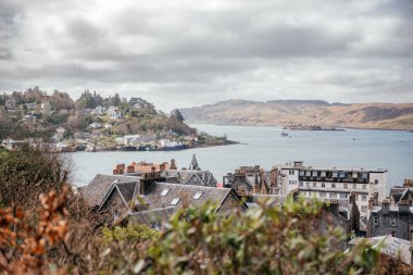 İskoçya 'nın Oban kentinin çatılarının manzarası, limanı, tepeleri ve kıyı mimarisi, turizm ve seyahat temaları için mükemmel.