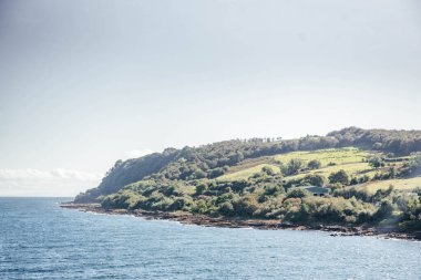 Arka planda manzaralı bir ada manzarası olan Arran Adası yakınlarındaki CalMac feribotu seyahat, ulaşım ve İskoç turizmi için idealdir..