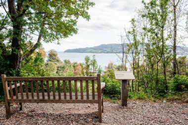 Huzurlu ahşap bank, yemyeşil yemyeşil bir İskoç gölüne bakıyor, uzak tepeler, ve huzurlu doğal ortam. Seyahat, peyzaj ve açık hava fotoğrafçılık projeleri için ideal