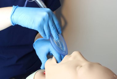 Laringeal maske solunum yolu (LMA) Bering, eldiven ve ameliyat önlüğü giyen bir sağlık uzmanı tarafından simüle edilmiş bir hasta solunum yoluna yerleştirildi.
