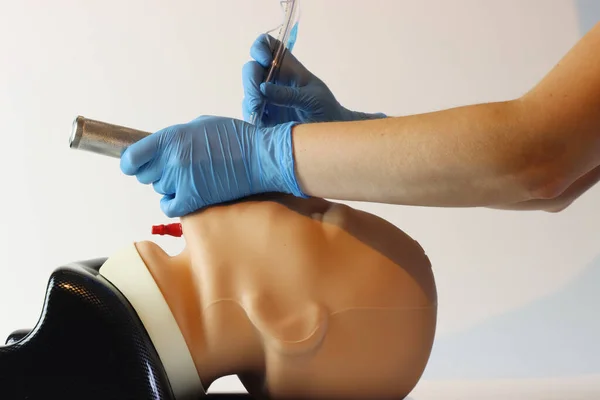 Laringoskop ve endotrakeal tüp takılmış bir hastaya tüp yutturmak. Cerrahi eldiven ve önlük giyen bir sağlık uzmanı..