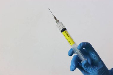 Ellerinde sıvı bulunan ketamin şırıngası tutan eldivenler takıyor.