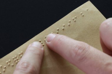 Kahverengi kağıtta körler alfabesi okuyan parmaklar